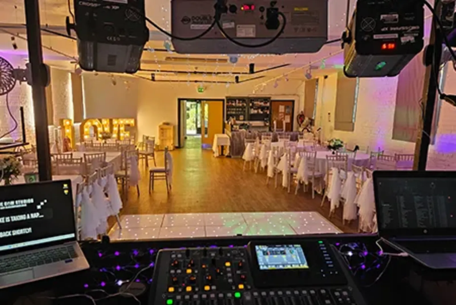 DJ booth with lighting and guests dancing at an event